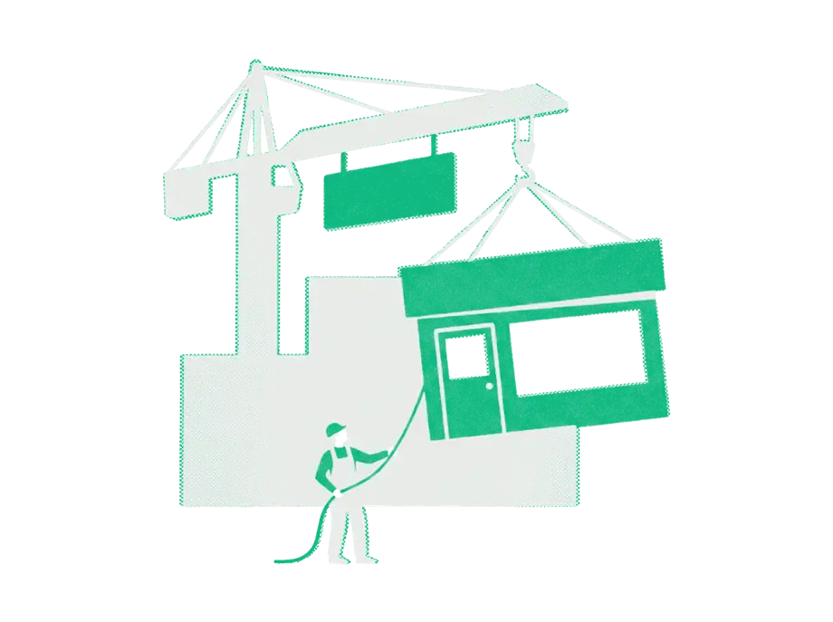 A crane lifting an emerald shopfront away from a plain black building while a worker guides it with a rope