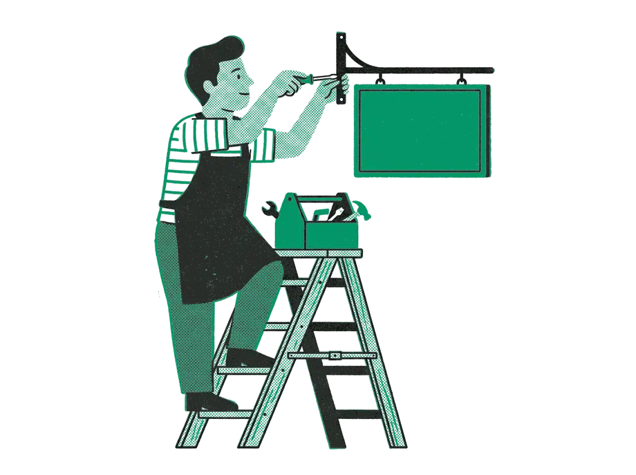 A shop owner on a stepladder fixing the bracket of a blank emerald sign, a toolbox open on the top step